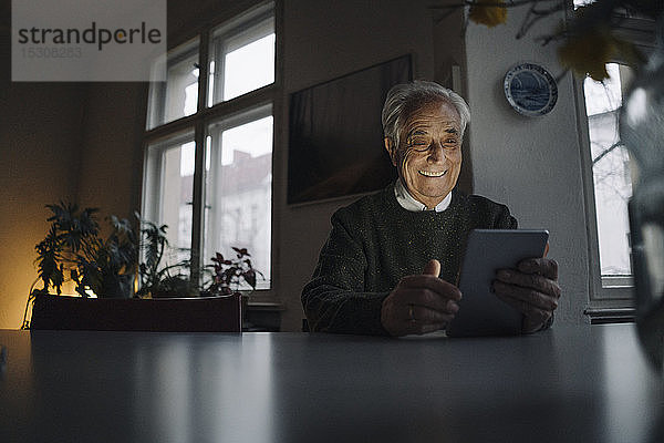 Lächelnder älterer Mann benutzt Tablette zu Hause