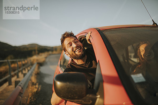 Mann auf einer Autoreise  der aus dem Autofenster schaut