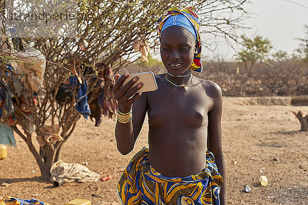 Junge Frau aus Mucubal  die ihr Smartphone überprüft  Tchitundo Hulo  Virei  Angola