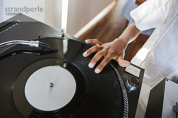Hand eines jungen DJs auf Vinyl-Schallplatte am Plattenteller
