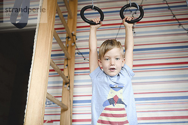 Porträt eines Jungen an Gymnastikringen hängend