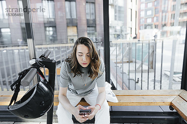Frau mit E-Scooter mit Smartphone