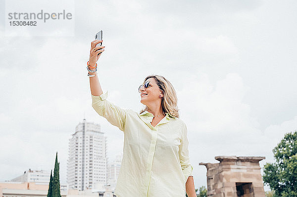 Ältere Frau fotografiert mit einem Smartphone in der Stadt