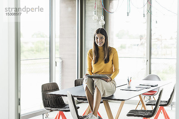 Porträt einer lächelnden jungen Geschäftsfrau mit Tablett im Büro