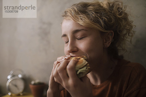 Porträt einer jungen Frau beim Hamburger-Essen
