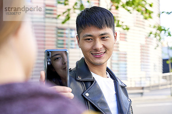 Lächelnder junger Mann macht ein Handyfoto von Frau in Barcelona  Spanien