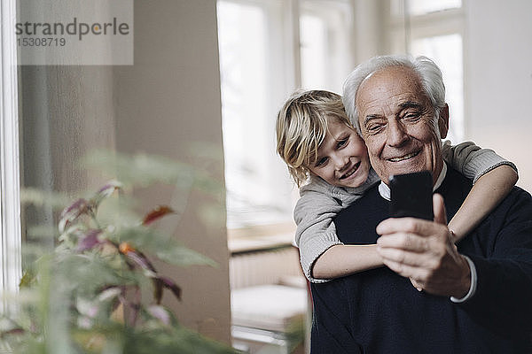 Glücklicher Großvater und Enkel telefonieren zu Hause