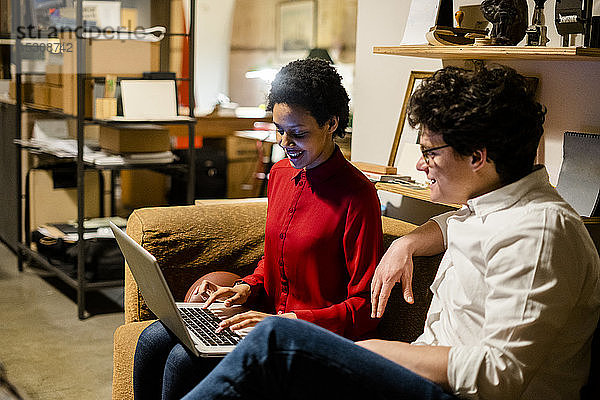 Geschäftsmann und Geschäftsfrau sitzen im Büro mit Laptop auf der Couch