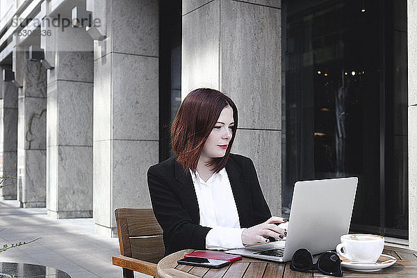 Geschäftsfrau  die im Café sitzt und einen Laptop benutzt