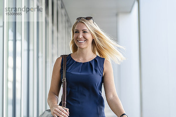 Porträt einer lächelnden blonden Geschäftsfrau in blauem Sommerkleid