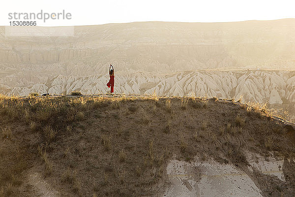 Frau macht eine Yoga-Übung in felsiger Landschaft in der Abenddämmerung  Goreme  Kappadokien  Türkei