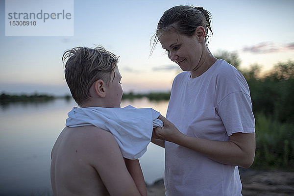 Mutter kümmert sich bei Sonnenuntergang um ihren Sohn am Seeufer