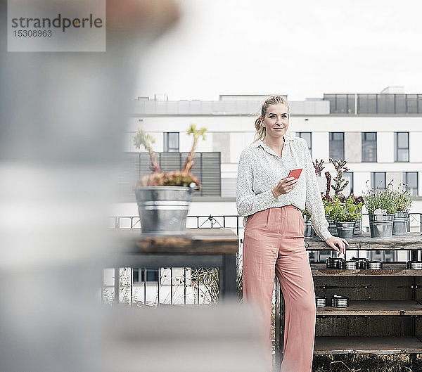 Porträt einer Gelegenheits-Geschäftsfrau mit Handy auf der Dachterrasse
