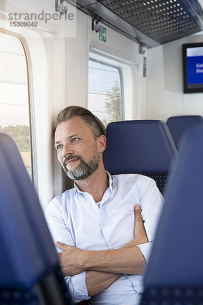 Ein reifer Mann sitzt in einem Zug und schaut aus dem Fenster