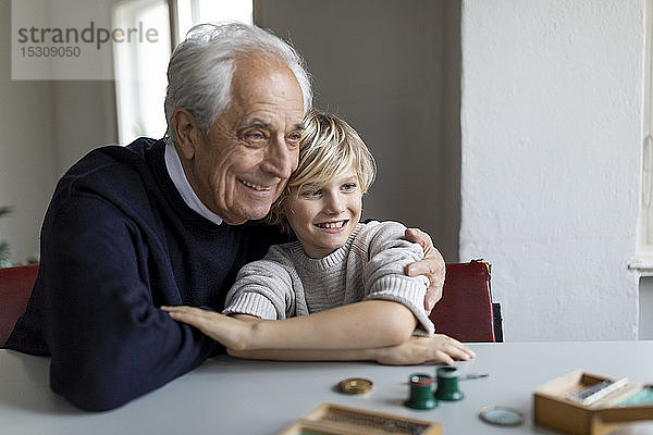 Uhrmacher und sein Enkel am Tisch sitzend