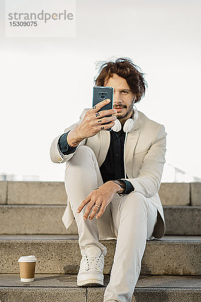 Mann mit tätowierten Fingern nimmt sich mit Smartphone