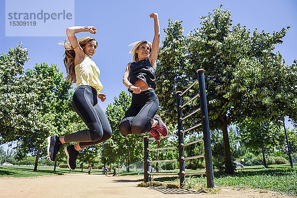 Athletische Frau und ihre Tochter springen gemeinsam in einem Park