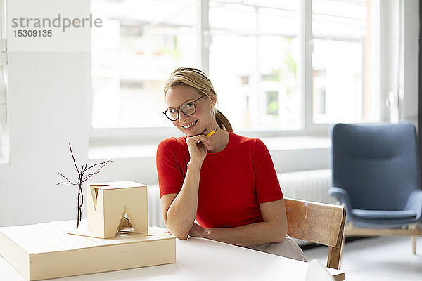 Junge Frau im Büro mit Architekturmodell auf dem Schreibtisch