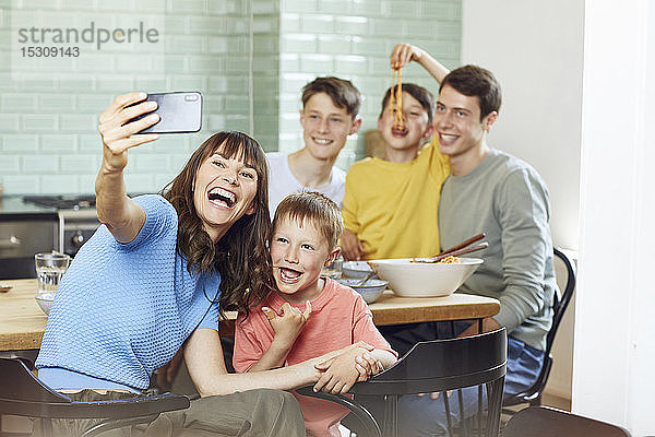 Mutter und ihre vier Söhne nehmen Smartphone-Selbstfahrer beim Mittagessen