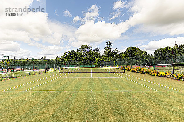 Sportnetz und Einzellinienmarkierungen auf leerem Tennisplatz gegen den Himmel