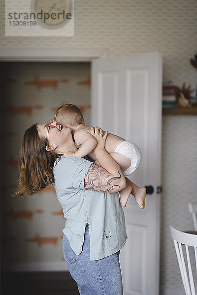 Lachende Mutter spielt mit ihrem kleinen Sohn in der Küche