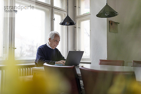 Älterer Mann benutzt Laptop zu Hause auf dem Tisch
