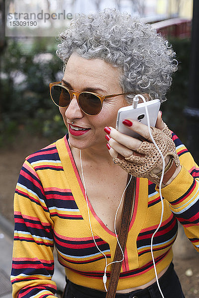 Porträt einer modischen  reifen Frau  die ihr Smartphone im Freien benutzt