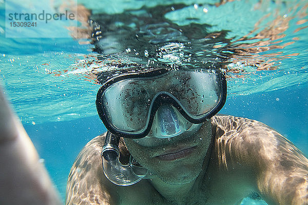 Porträt eines Mannes mit Taucherbrille und Schnorchel beim Selbstversuch unter Wasser
