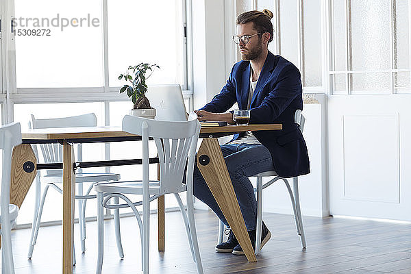 Geschäftsmann mit Laptop am Tisch im modernen Büro