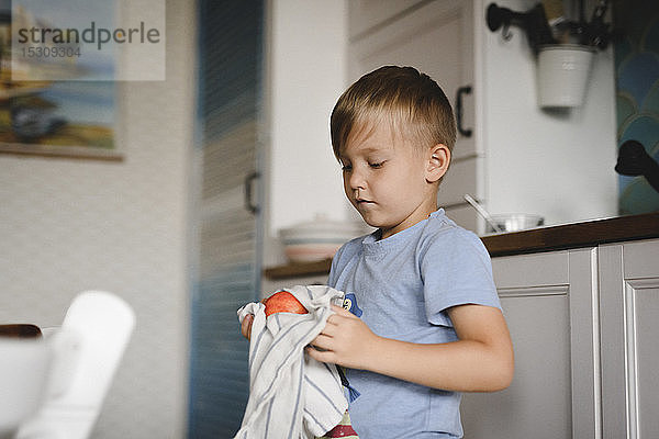 Porträt eines kleinen Jungen beim Pfirsichtrocknen mit Küchentuch