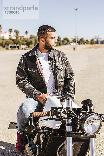 Porträt eines bärtigen jungen Mannes auf seinem Motorrad sitzend