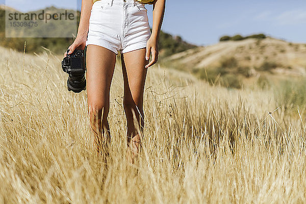 Unterer Teil einer jungen Frau mit Kamera beim Gehen in entlegener Landschaft  Granada  Spanien