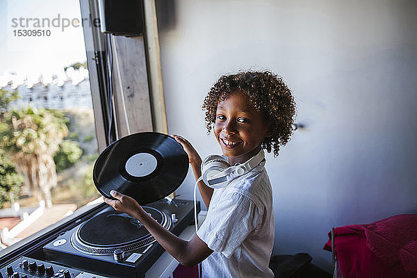 Porträt eines glücklichen jungen DJs mit Schallplatte