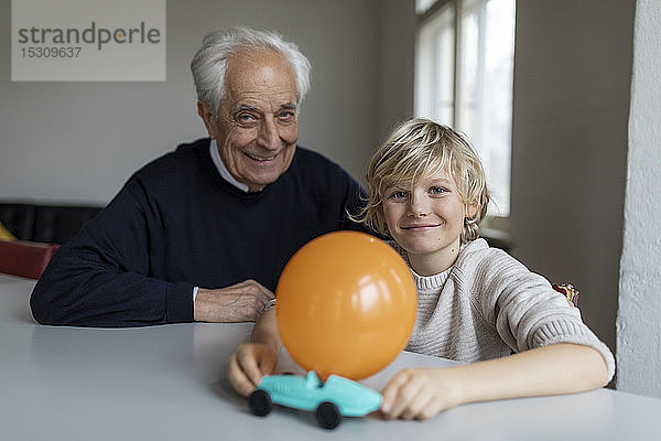 Glücklicher Großvater und Enkel spielen zu Hause mit Spielzeugauto und Ballon