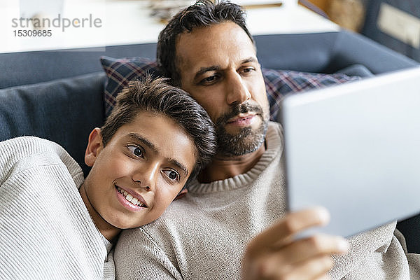 Glückliche Vater und Sohn benutzen Tablette auf der Couch im Wohnzimmer