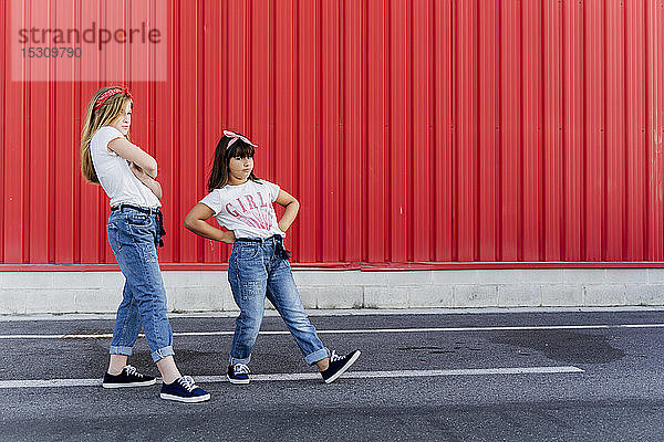 Zwei Schwestern stehen vor einer roten Wand