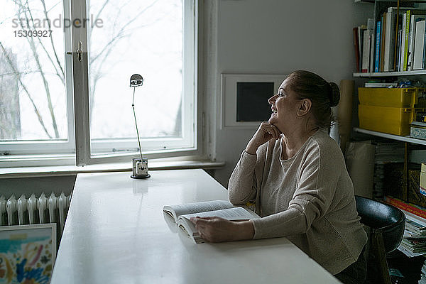 Glückliche ältere Frau liest zu Hause ein Buch