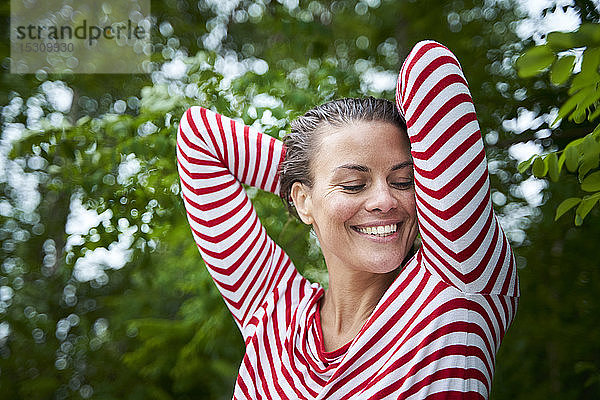 Porträt einer glücklichen Frau mit nassem Haar und gestreiftem Oberteil in Natur