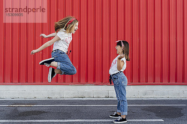Schwestern springen auf die Strasse vor die rote Mauer