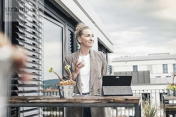 Geschäftsfrau mit Kaffeetasse und Tablette auf der Dachterrasse