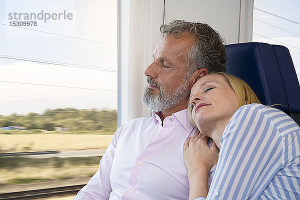 Paar reist mit dem Zug  die Frau stützt sich auf die Schulter des Mannes