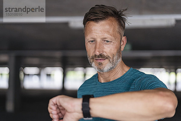 Porträt eines sportlichen Mannes beim Prüfen seiner Smartwatch