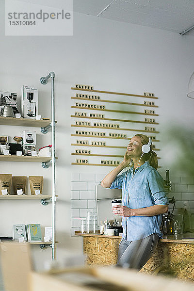Junge Frau hört Musik  trägt Kopfhörer  steht im Café