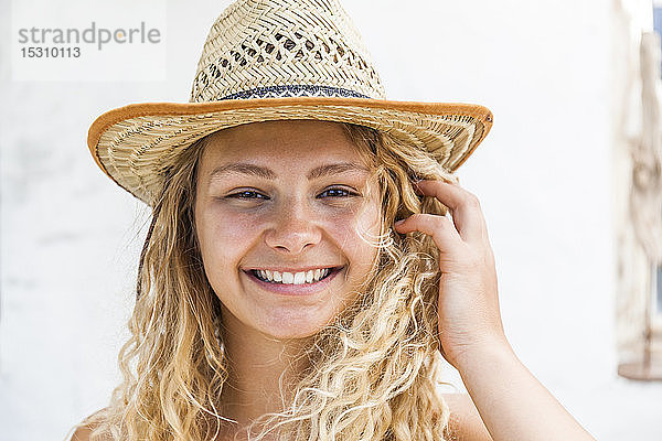 Porträt einer lächelnden blonden Frau mit Strohhut
