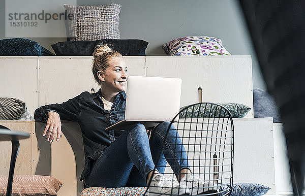 Lächelnde Gelegenheits-Geschäftsfrau benutzt Laptop in Büro-Lounge