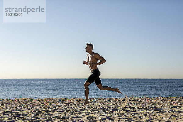 Barbrüstiger Mann joggt am Strand
