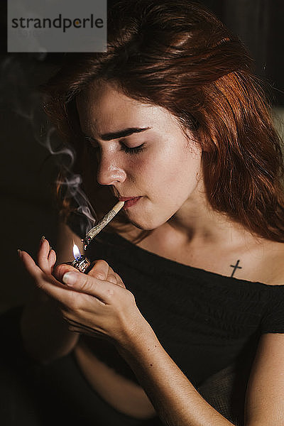Junge Frau raucht zu Hause Marihuana