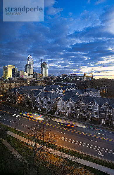 Fahrzeuge auf der Straße vor Gebäuden in Charlotte gegen bewölkten Himmel bei Sonnenuntergang