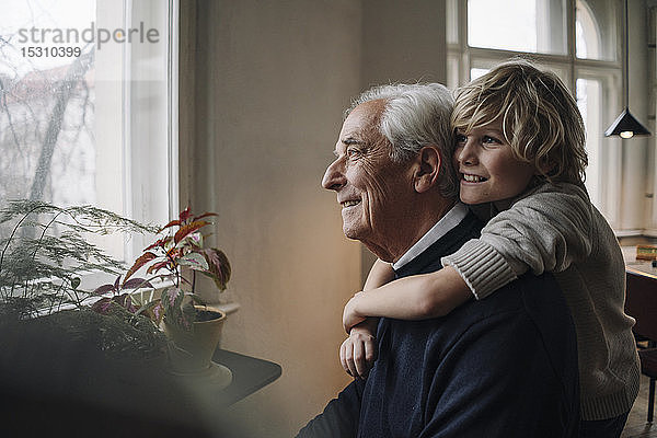 Glücklicher Enkel umarmt Großvater zu Hause