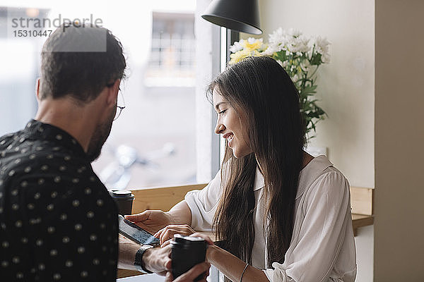 Junges Paar mit Einwegbecher und Smartphone in einem Cafe